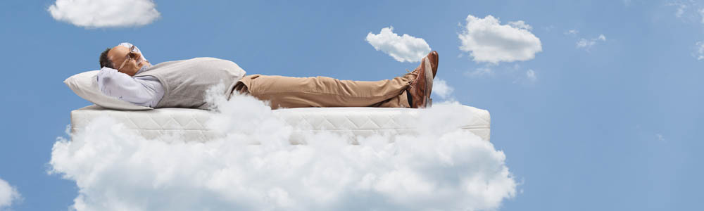Older man lying back with his hands behind his head, floating in the clouds. Bright blue sky and white clouds floating around him. Older man lying back with his hands behind his head, floating in the clouds. Bright blue sky and white clouds floating around him.